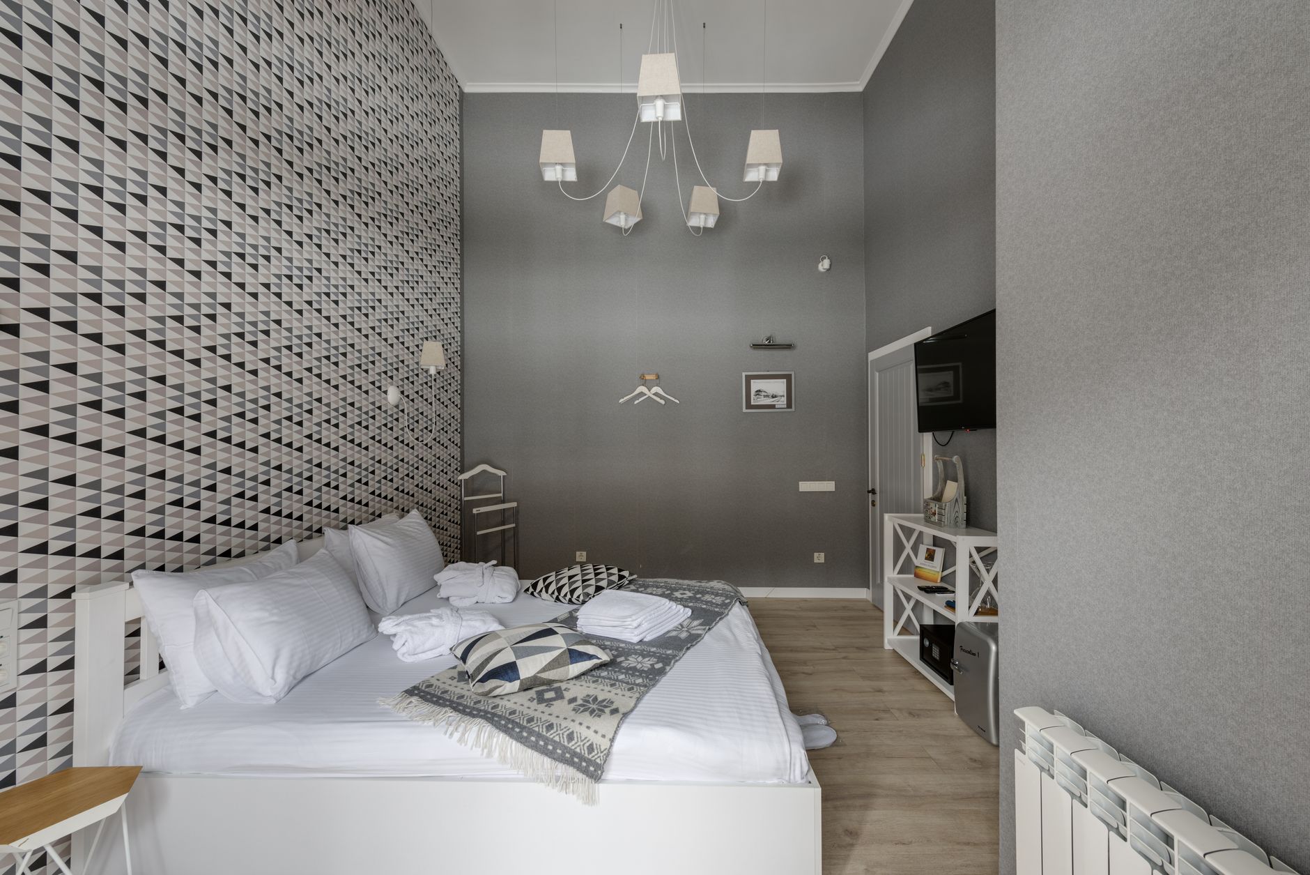 Bright hotel room with a made white bed and a tall window